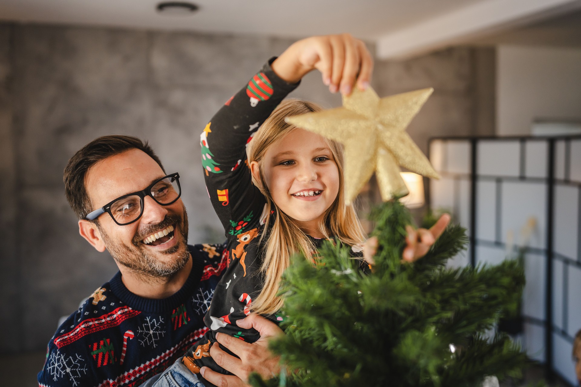 Father and daughter decorate Christmas tree indoors together